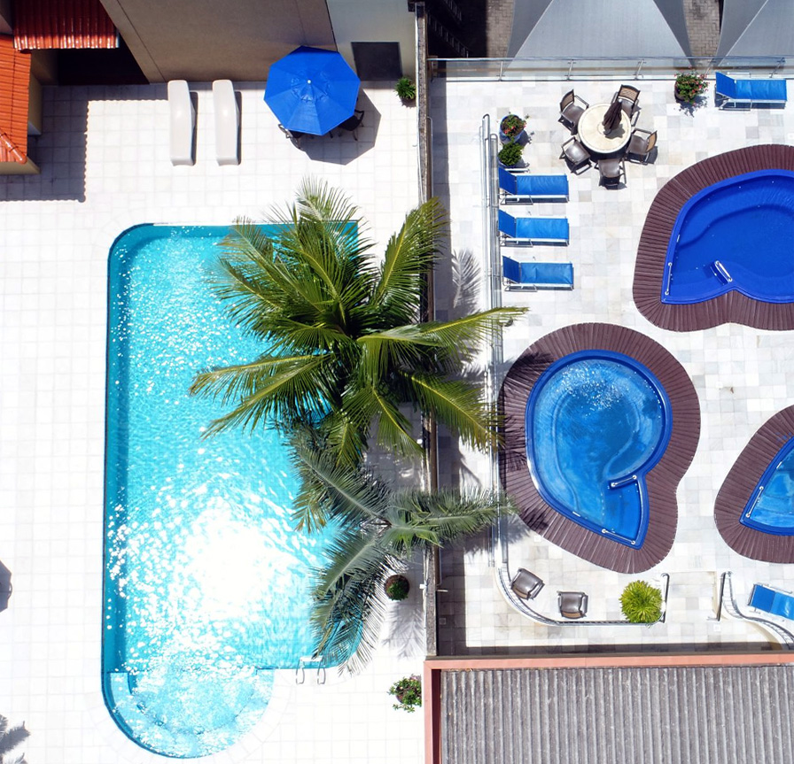 Vista aérea das piscinas do Águas do Iguaçu, um hotel barato em Foz do Iguaçu, que oferece áreas de lazer com piscina ao ar livre e espreguiçadeiras para relaxamento.