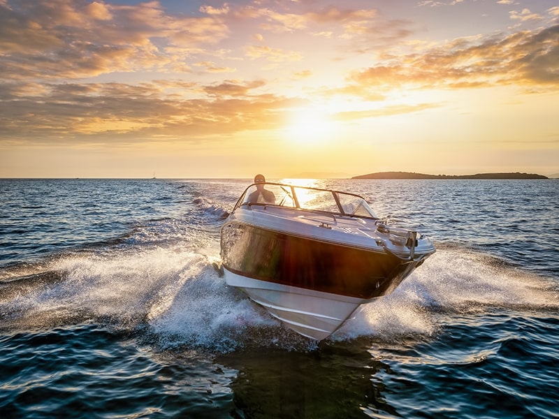 Imagem de um barco navegando ao pôr do sol, exibindo velocidade e elegância no mar, destacando-se como seria o evento do Foz Boat Show 2024.