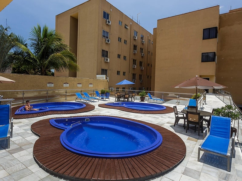 Jacuzzis ao ar livre rodeadas por espreguiçadeiras e guarda-sóis.