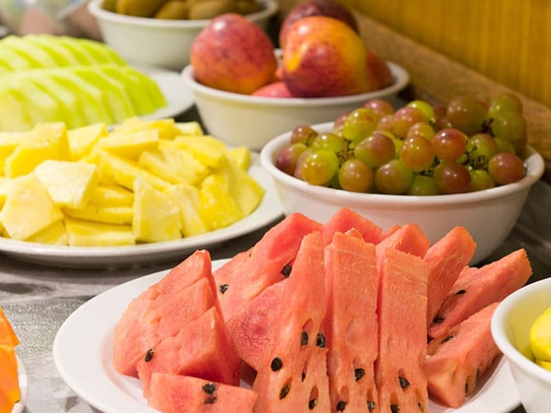 Buffet de café da manhã - Mesa farta com frutas frescas, incluindo melancia, abacaxi e uvas.