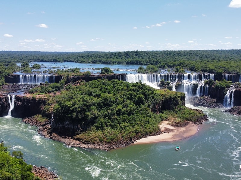 Vista panorâmica das majestosas Cataratas do Iguaçu com vegetação exuberante ao redor.